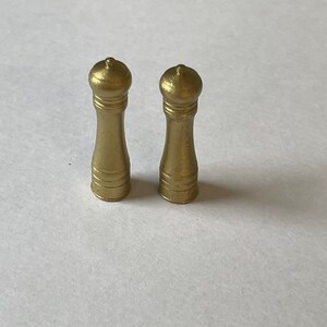 May include: Two gold-colored salt and pepper shakers with a classic design.