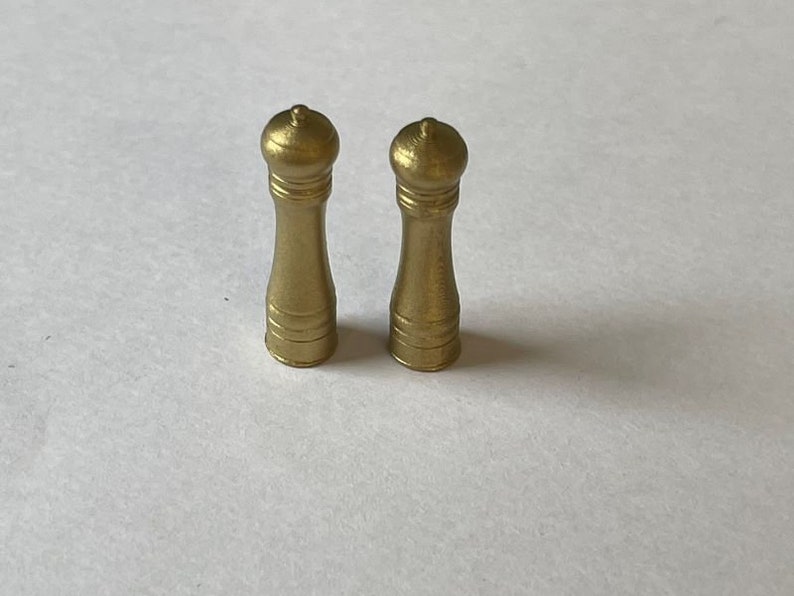 May include: Two gold-colored salt and pepper shakers with a classic design.