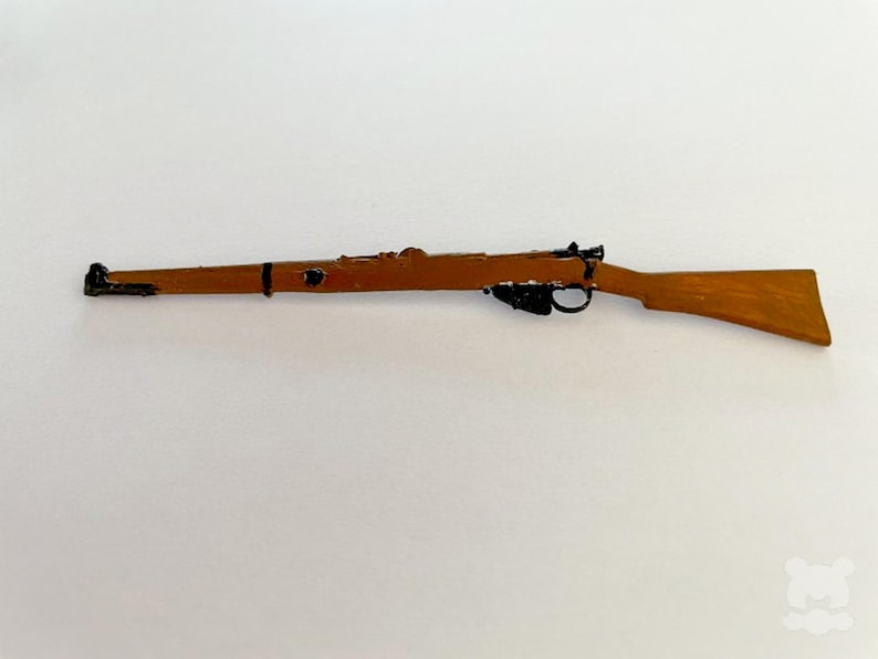 May include: A wooden toy rifle with a brown finish and black accents. The rifle features a trigger, a sight, and a stock. The toy rifle is a replica of a classic firearm.
