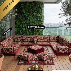 Peut inclure: Un ensemble de salon extérieur en forme de U avec un motif rouge, marron et orange. L'ensemble comprend des coussins, un tapis et un ottoman central. L'ensemble mesure 320 cm de large et 180 cm de profondeur.