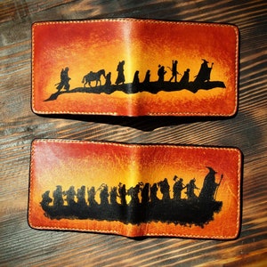 Puede incluir: Dos carteras de cuero con un fondo de puesta de sol y una silueta de la Comunidad del Anillo de El Señor de los Anillos.