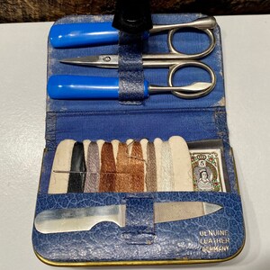 May include: A blue leather sewing kit with a variety of tools, including scissors, a needle, thread, and a nail file. The kit also includes a small card with a picture of a woman and the text "Genuine Leather Germany".