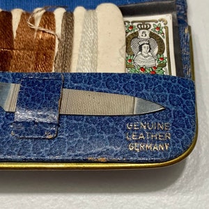 May include: A blue leather sewing kit with a metal nail file and spools of thread. The kit has a label that reads "Genuine Leather Germany".