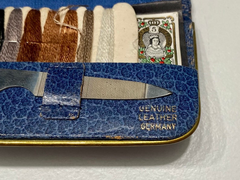 May include: A blue leather sewing kit with a metal nail file and spools of thread. The kit has a label that reads "Genuine Leather Germany".