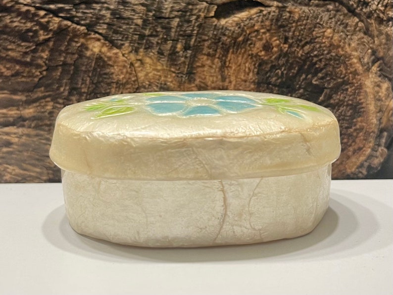 May include: A white oval trinket box with a blue and green floral design on the lid.