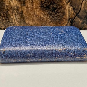 May include: A small, blue, leather-bound book with a textured cover.