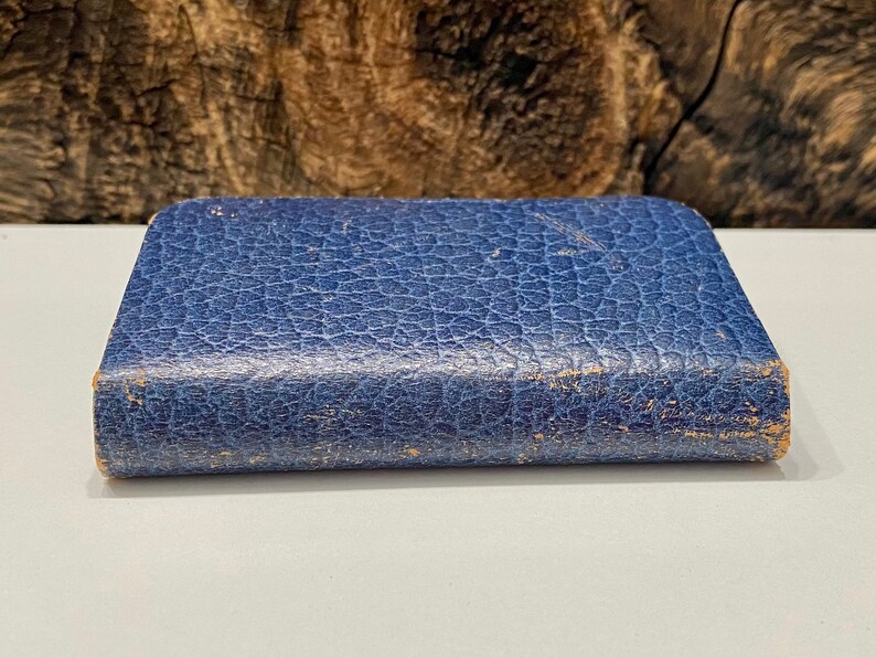 May include: A small, blue, leather-bound book with a textured cover.