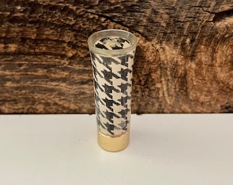May include: A clear plastic tube with a black and white houndstooth pattern. The tube has a gold metal bottom.