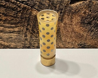 May include: A yellow and black polka dot lipstick tube with a gold bottom.