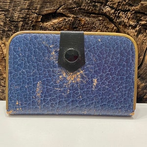 May include: A blue leather card holder with a gold trim and a black button closure.