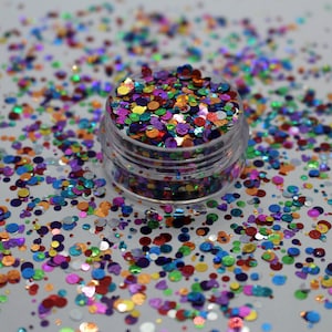 May include: A small clear jar filled with colourful iridescent glitter confetti. The glitter is in various sizes and shapes, with a mix of round and irregular pieces.
