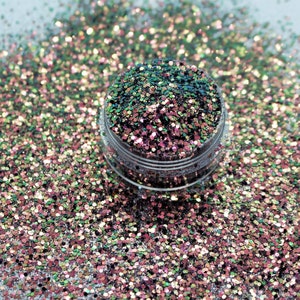 May include: A close-up of a jar filled with iridescent glitter in shades of green, pink, and gold. The glitter is scattered around the jar on a light gray surface.