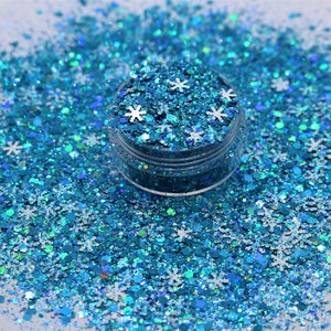 May include: A small jar filled with blue and iridescent glitter with white snowflake shapes.