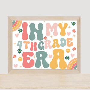 May include: A framed print with a white background and colorful text that reads "In My 4th Grade Era". The text is in a retro font style and is surrounded by flowers, hearts, and stars.