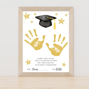 Peut inclure: Une impression de diplôme encadrée avec un mortier noir et une gland jaune, des empreintes de mains dorées et des étoiles. L'impression comprend le texte "I LEARNED, I GREW, I HAD FUN..." et le nom "Olivia" avec l'année "2026".