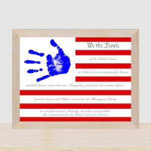 May include: A framed print of the Preamble to the United States Constitution with a blue handprint in the upper left corner and a red, white, and blue striped background.