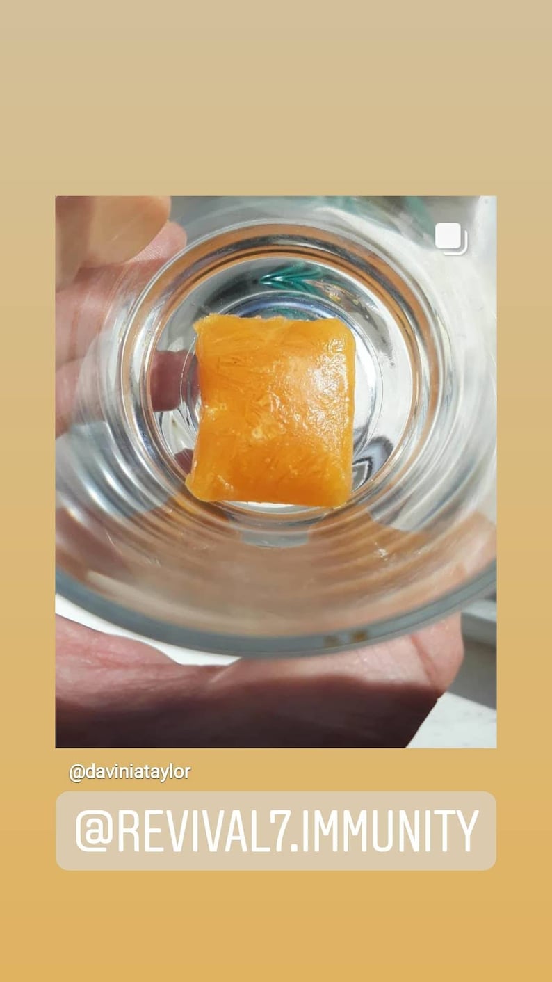 May include: A close-up of a small, square, orange-colored gummy candy in a clear glass dish. The candy has a slightly textured surface. The text "@REVIVAL7.IMMUNITY" is visible below the image.