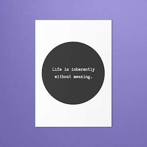 May include: A rectangular white print featuring a large, solid black circle in the center. Inside the circle, the text "Life is inherently without meaning." is printed in a white, typewriter-style font, centered horizontally.