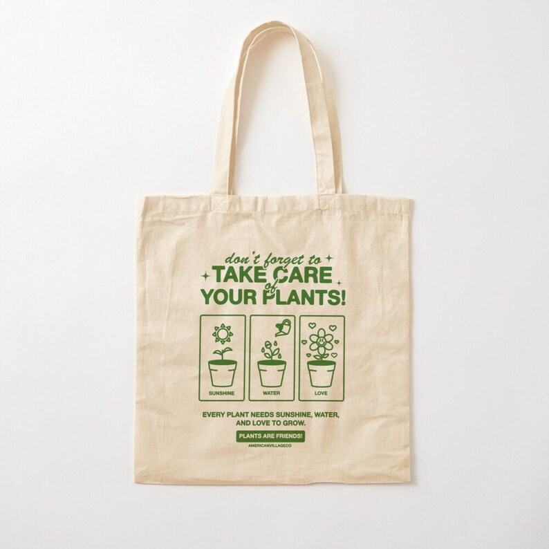 May include: A beige tote bag with a green graphic that says "don't forget to + TAKE CARE of YOUR PLANTS!" with three icons representing sunshine, water, and love. The text below the icons says "Every plant needs sunshine, water, and love to grow. PLANTS ARE FRIENDS!"