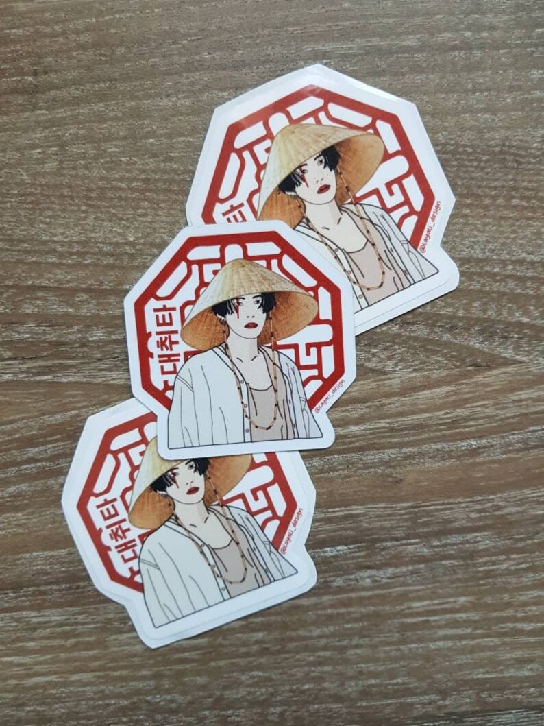 May include: Three white octagonal stickers with red borders and a stylized illustration of a person wearing a conical hat and a white shirt. The text "대답타" is written in Korean on the stickers.