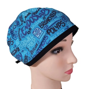 May include: Blue and purple medical scrub hat with a black trim. The hat is covered in medical terms, including "Endoscopy", "Bronchoscopy", "Polyps", "Sedation", "EUS", "Prep", "Reflux", "Oesophagus", "Small Bowel", "Ulcers", and "Drink Me".
