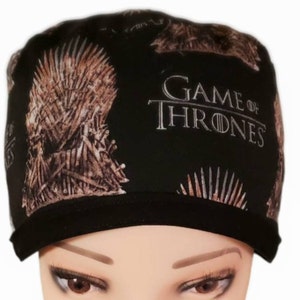 May include: Black scrub cap featuring a brown Iron Throne design and the text "GAME OF THRONES" in white. The cap has a black brim and is made of a soft, flexible material.