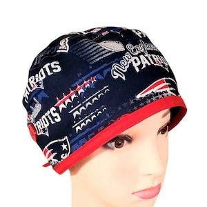 May include: A blue and red scrub hat with a button closure. The hat features a New England Patriots logo and the words "New England Patriots" and "Patriots" repeated throughout the design.