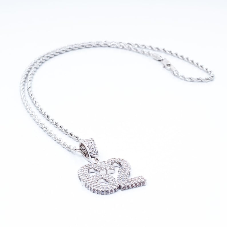 Puede incluir: Un collar de cadena de plata con un colgante que presenta el n&uacute;mero 82, incrustado con piedras de circonita c&uacute;bica transparentes.