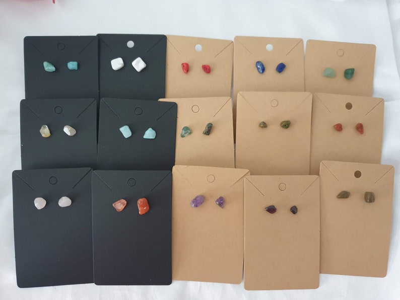 May include: Assortment of 10 pairs of gemstone earrings displayed on small cards. The earrings are made of various natural stones, including turquoise, white, red, blue, green, amethyst, and brown.