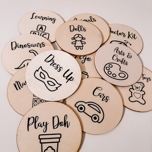 Pu&ograve; includere: Un set di 10 etichette rotonde in legno con testo nero e illustrazioni. Le etichette sono per diverse categorie di giocattoli, tra cui dinosauri, bambole, auto, travestimenti, arti e mestieri, plastilina, apprendimento e altro ancora.