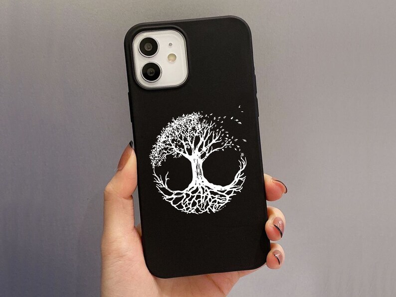 May include: Black phone case with a white tree of life design. The tree is circular, with detailed branches and roots. The case has a matte finish and is shown on a grey background.