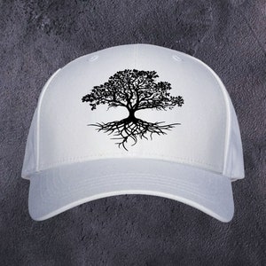 May include: A white baseball cap with a black tree design. The tree illustration shows a detailed crown and roots, creating a nature-inspired graphic. The cap has a curved peak and a classic, adjustable fit.