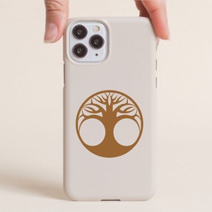 May include: A beige phone case with a brown tree of life design. The tree is a circular emblem with a detailed, symmetrical pattern. The case has a camera module with three lenses.