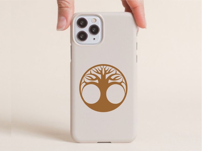 May include: A beige phone case with a brown tree of life design. The tree is a circular emblem with a detailed, symmetrical pattern. The case has a camera module with three lenses.