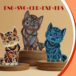 Può includere: Tre gatti di carta realizzati a mano, con disegni intricati e strati, in colori marrone, arancione e blu. I gatti sono seduti su basi di legno.