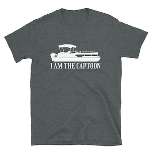 May include: Dark gray t-shirt featuring a white graphic of a pontoon boat with the text "I AM THE CAPTOON" in a bold, sans-serif font. The boat design includes a canopy and motor, perfect for boating enthusiasts.