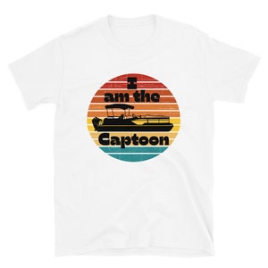 May include: White t-shirt with a graphic of a pontoon boat inside a circular design with a sunset color scheme. The text "I am the Captoon" is printed above and below the boat illustration.