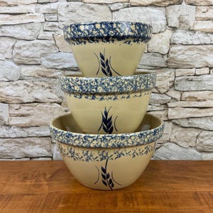 May include: A set of three ceramic mugs with a speckled, matte finish. The mugs are in shades of cream, light gray, and dark gray. Each mug has a simple, minimalist design, perfect for coffee or tea.