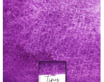May include: A close-up of a purple watercolor wash with a small square of the same color in the bottom right corner. The square has the text "Tiny Manganese Violet" written on it.
