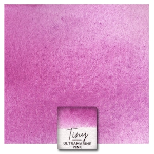 May include: A watercolor paint sample in a small square pan. The paint is a vibrant pink color with a slightly textured surface. The pan is labeled "Tiny Ultramarine Pink."