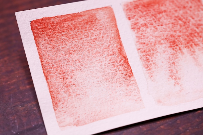 May include: Two watercolour swatches on white paper. The left swatch is a gradient of red to white. The right swatch is a gradient of red to white with a vertical brushstroke pattern.