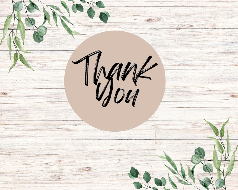 May include: A round, light brown sticker with the words "Thank You" in black script. The sticker is set against a light wood background, with green eucalyptus leaves and branches in the corners.