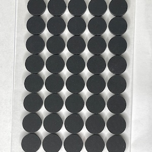 May include: A sheet of 50 black round adhesive felt pads. The pads are arranged in a grid pattern on a clear plastic sheet.