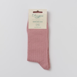 Pode incluir: Um par de meias de lã merino rosa empoeirado com uma textura de malha canelada. As meias são embaladas com uma etiqueta creme que diz "Doogan Donegal Ireland" e "Merino Wool Socks". A etiqueta também diz "Classic Collection Fine Irish Socks".