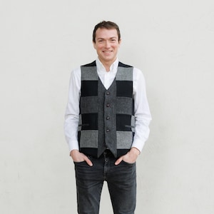 Peut inclure: Un gilet patchwork gris et noir avec un col en V. Le gilet a une fermeture boutonnée sur le devant et deux poches. La personne porte une chemise blanche à col et un jean foncé.