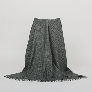 Peut inclure: Une couverture en laine à carreaux noirs et bleus avec des franges sur les bords.