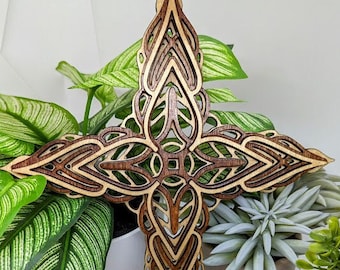 May include: A wooden cross with a intricate, laser-cut design. The cross is made of two different shades of wood, creating a beautiful contrast. The cross is a beautiful piece of art that would be perfect for any home.