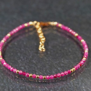 May include: A dainty bracelet featuring small pink beads and gold accents. The bracelet has a simple design and is ideal for everyday wear.