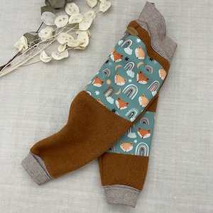 Könnte beinhalten: Braune Fleecehose mit einem blauen und weißen Fuchs-Druck. Die Hose hat einen gestreiften Bund und einen braunen Bund.