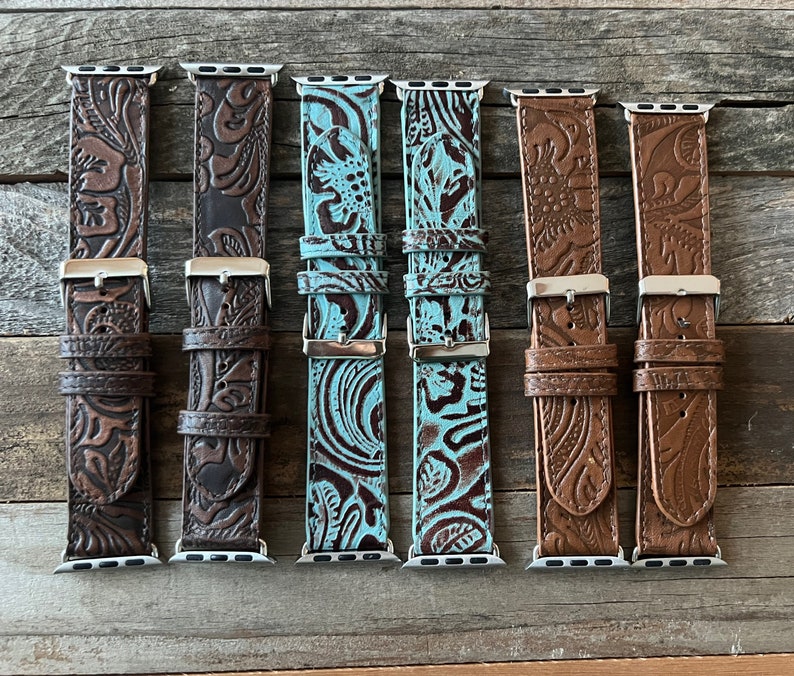 May include: Six different Apple Watch bands with embossed floral patterns. The bands are in brown, dark brown, and turquoise.